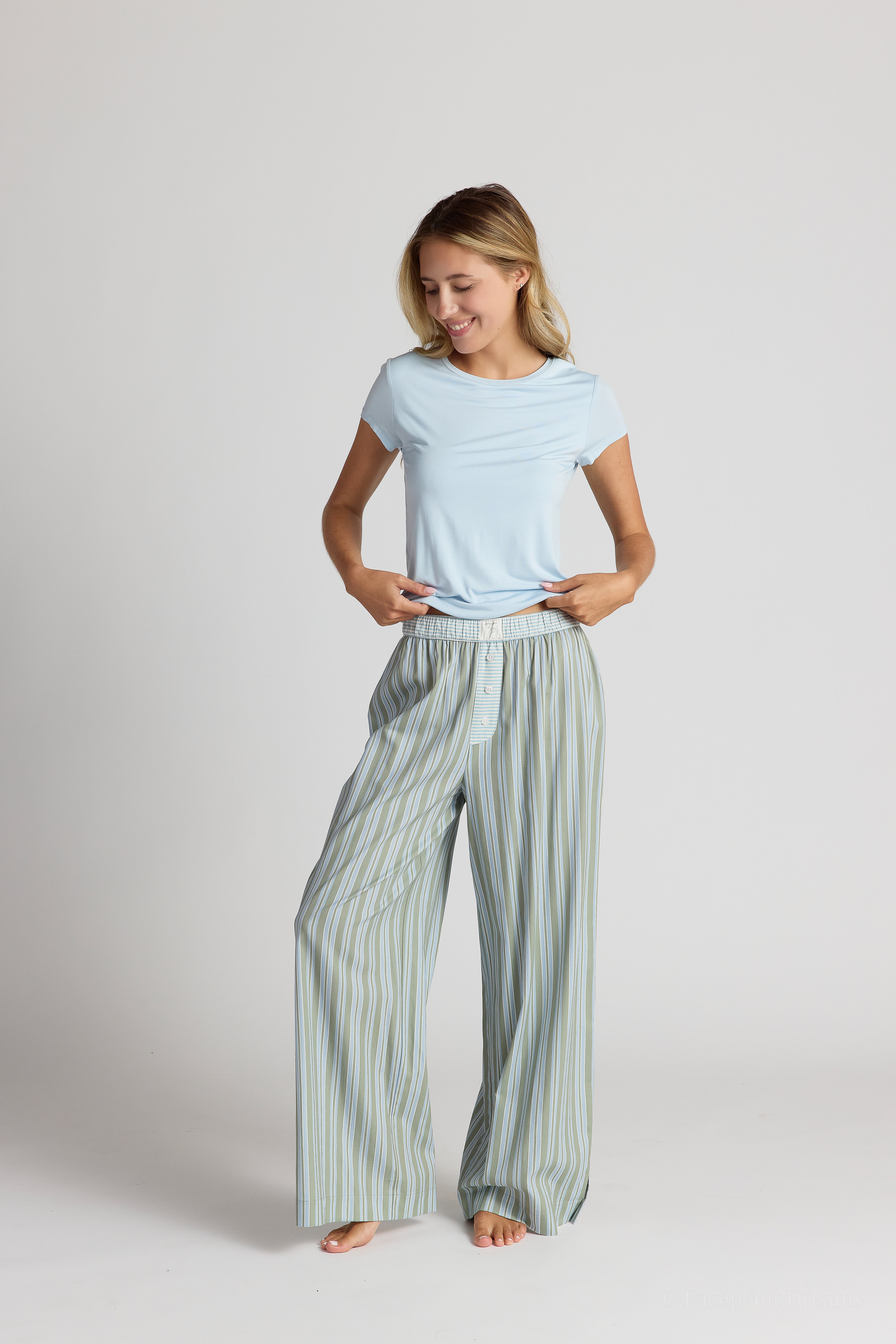 Woman wearing a light blue top and green striped pants on a white background
