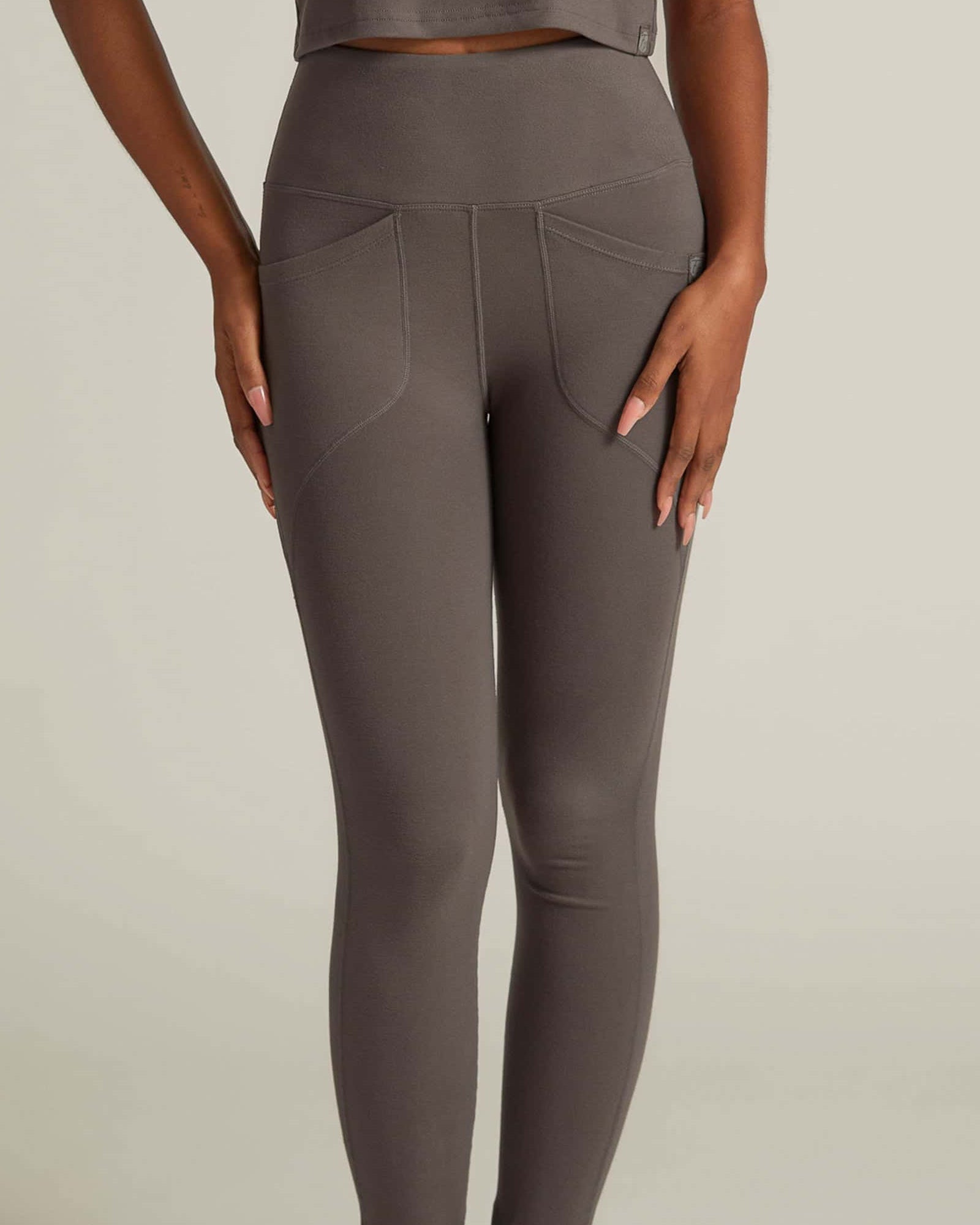 Person wearing brown leggings and crop top on a neutral background