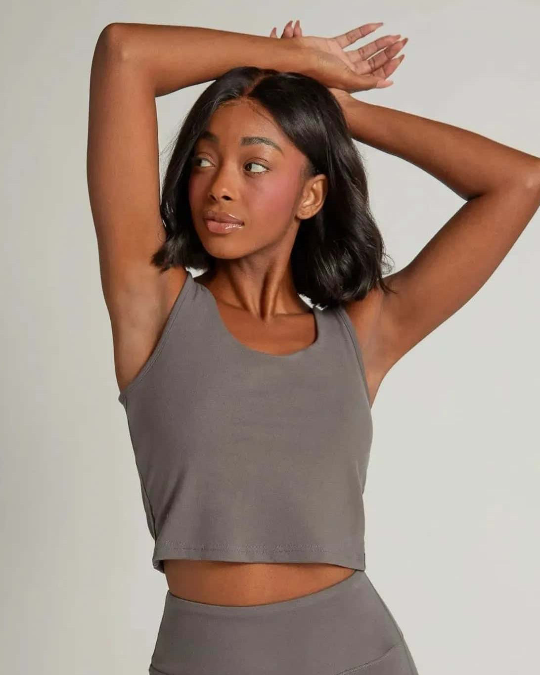 Woman wearing a gray athletic outfit posing against a plain background