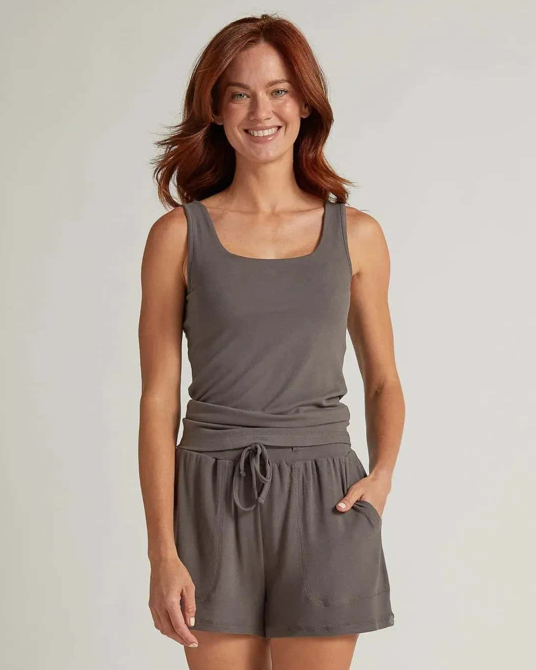 A woman wearing gray short lounge shorts with a drawstring waistband and a matching tank top
