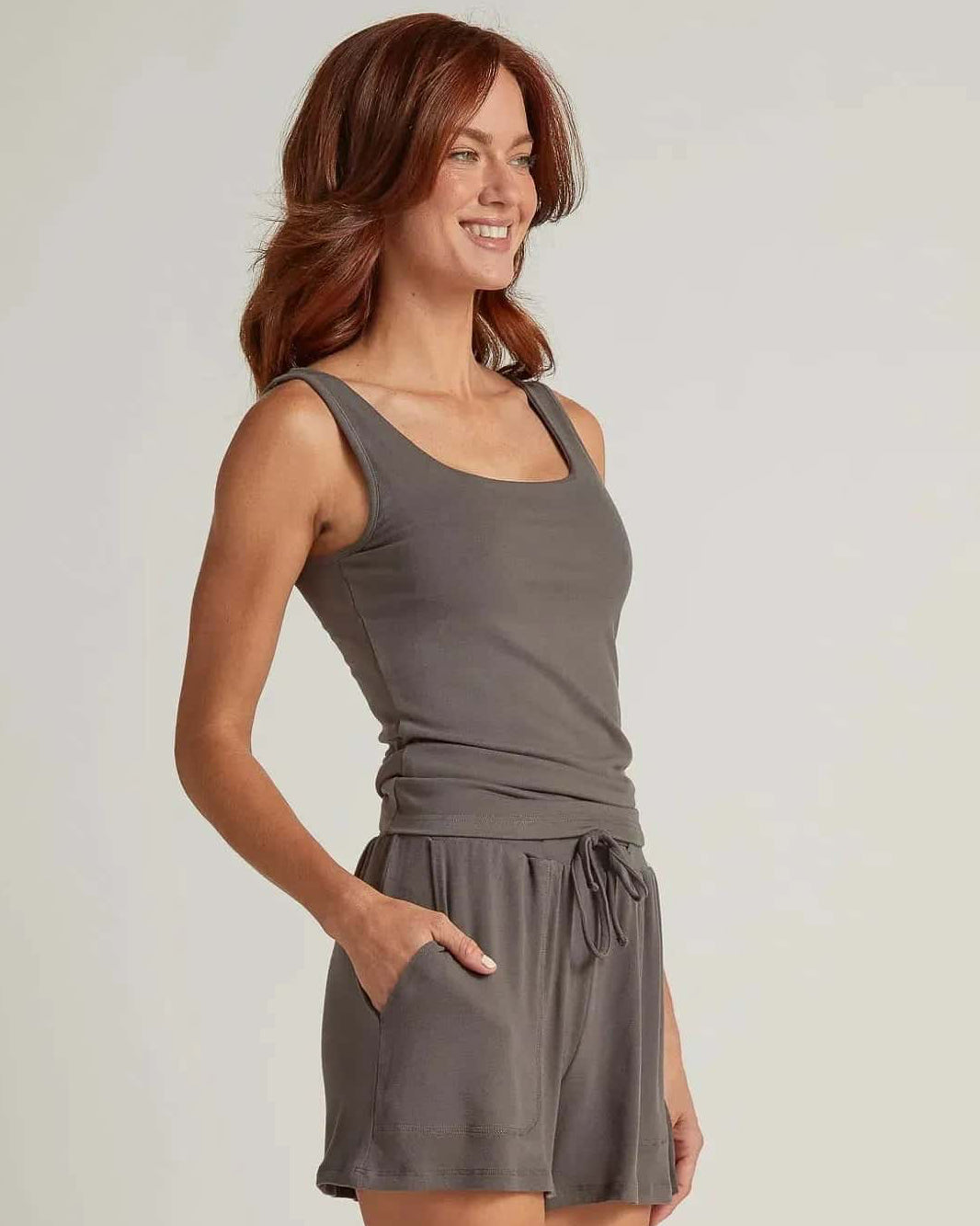 A woman wearing gray short lounge shorts with a drawstring waistband and a matching tank top