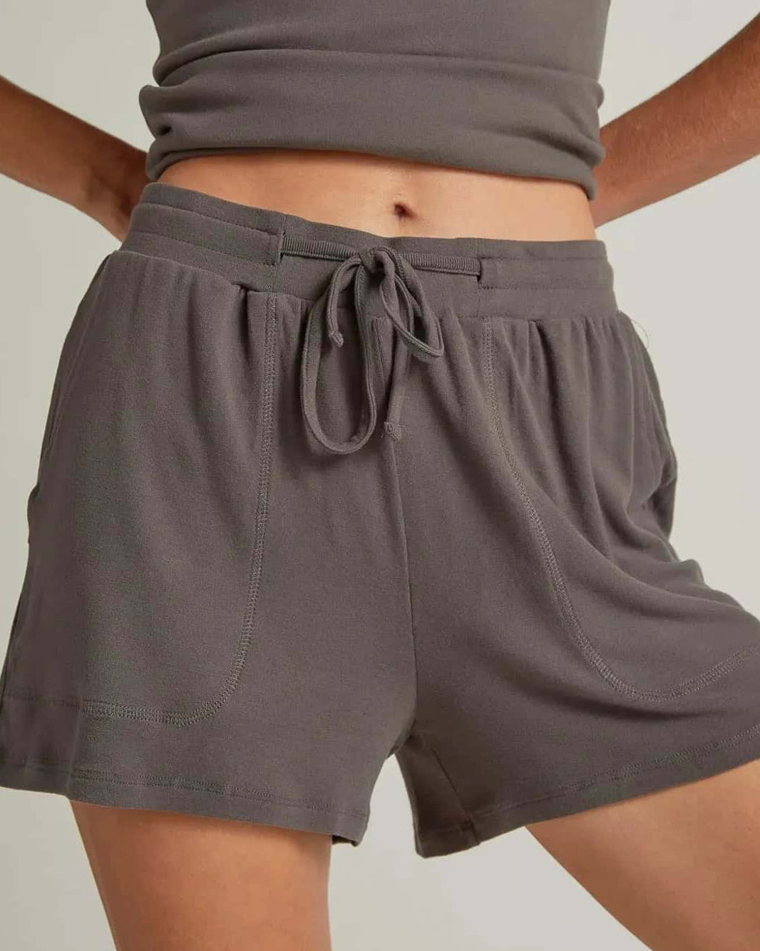 A woman wearing gray short lounge shorts with a drawstring waistband.