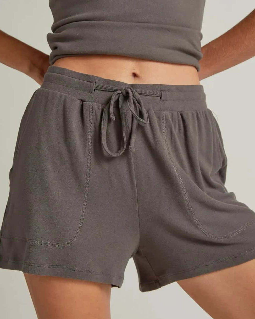 Person wearing a gray tank top and shorts on a plain background
