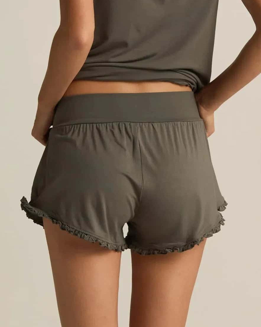 A pair of grey ruffle shorts with an elastic waistband and loose leg openings with ruffled edge detail.