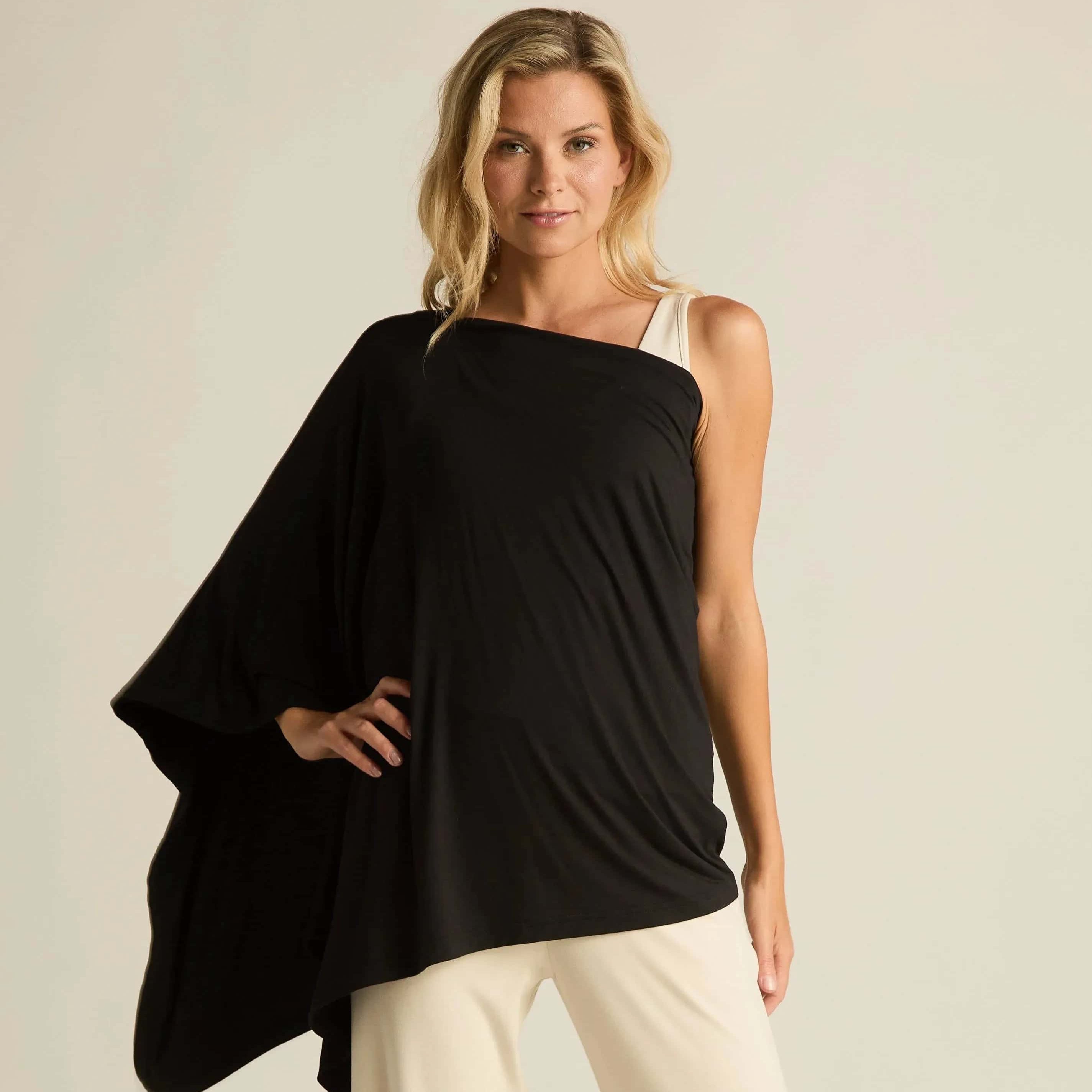 Woman wearing a black one-shoulder top and beige pants against a plain background