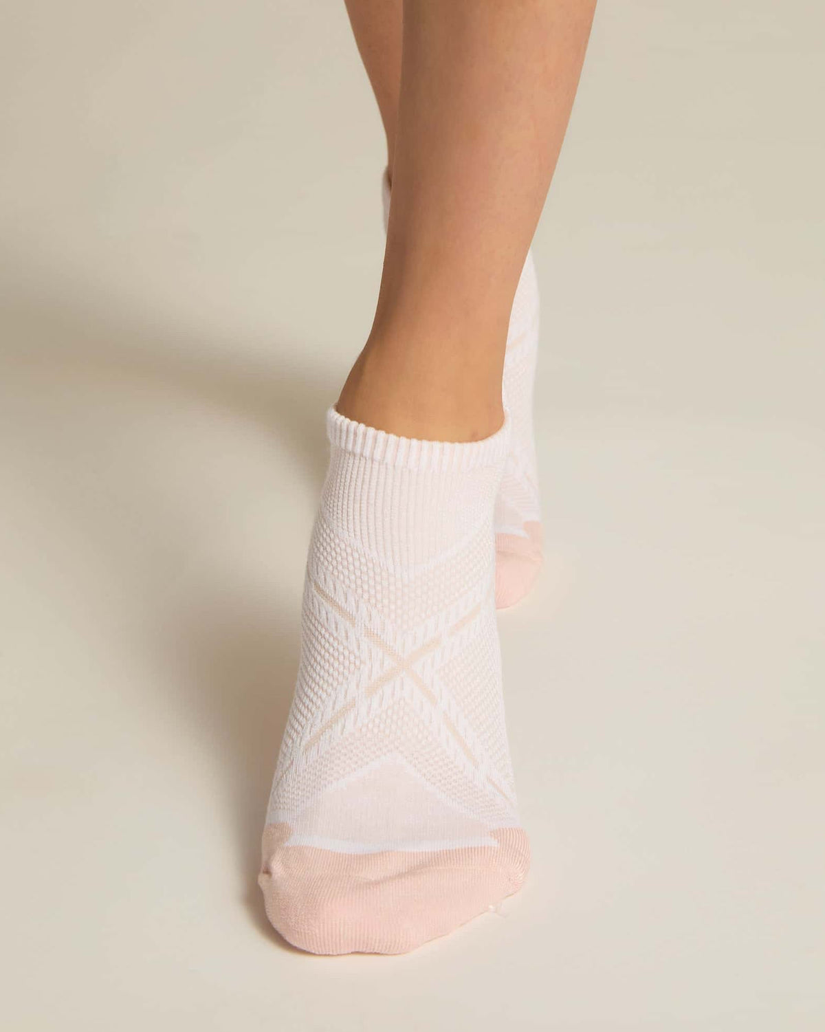 A pair of pink ankle socks with padding at the toe and heel areas, displayed on a person's feet against a white background.
