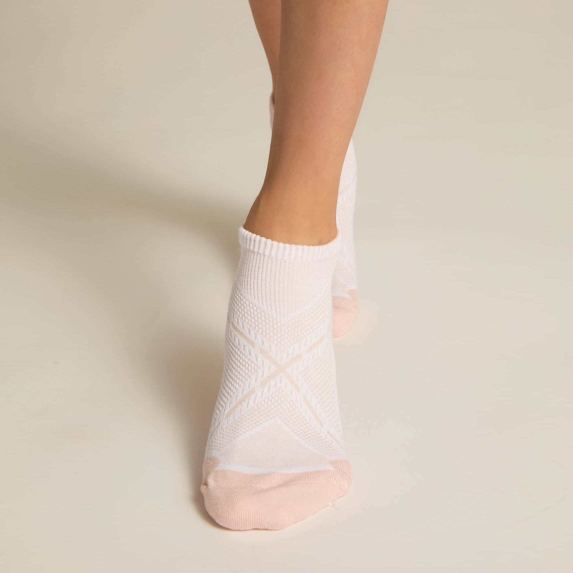 A pair of pink ankle socks with padding at the toe and heel areas, displayed on a person's feet against a white background.