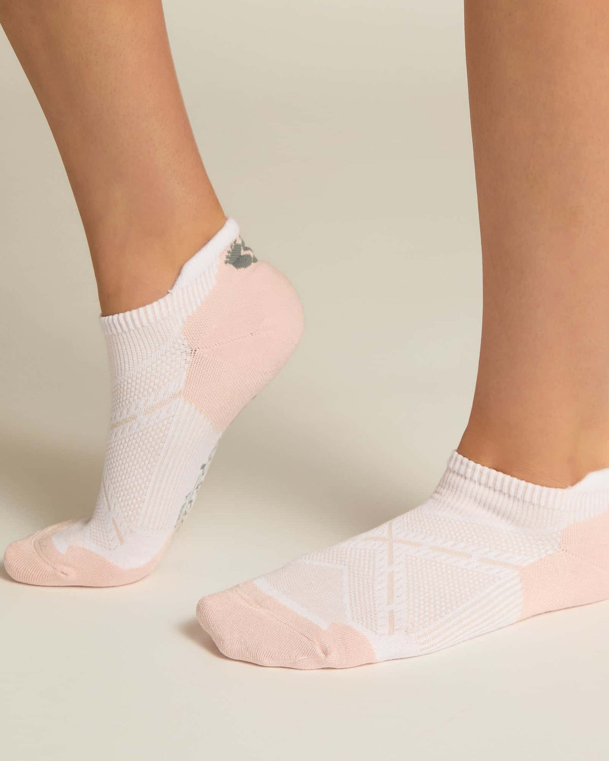 A pair of pink ankle socks with padding at the toe and heel areas, displayed on a person's feet against a white background.