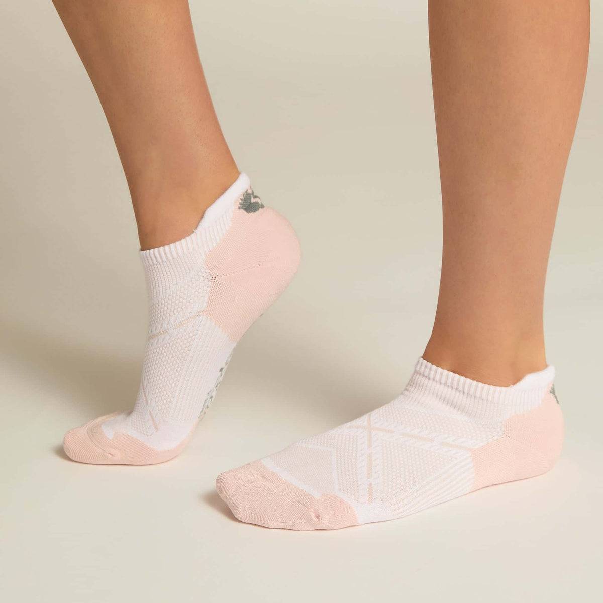 A pair of pink ankle socks with padding at the toe and heel areas, displayed on a person's feet against a white background.