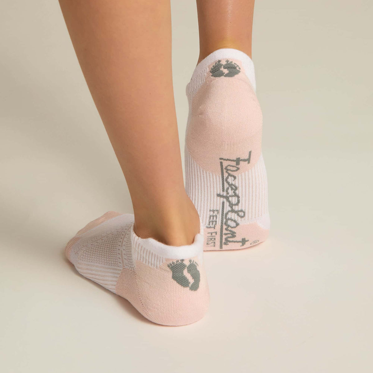 A pair of pink ankle socks with padding at the toe and heel areas, displayed on a person's feet against a white background.