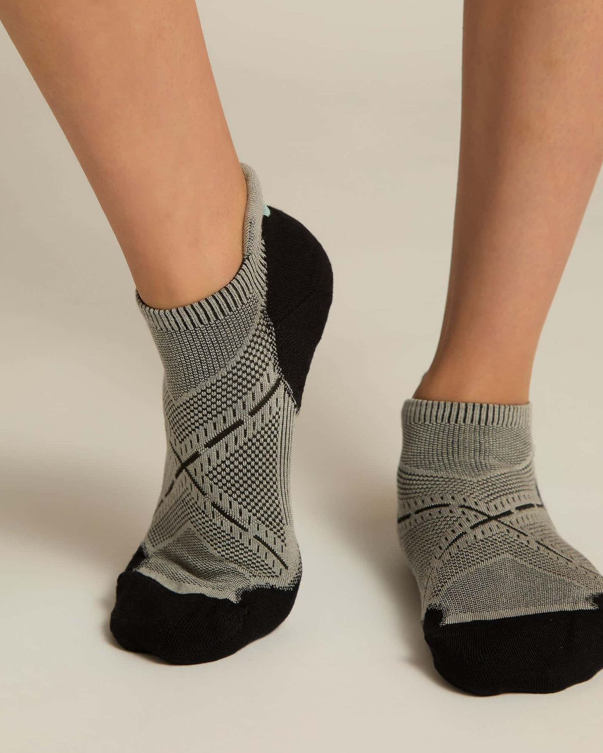 A pair of gray ankle socks with a geometric pattern, featuring black at the toe and heel sections.