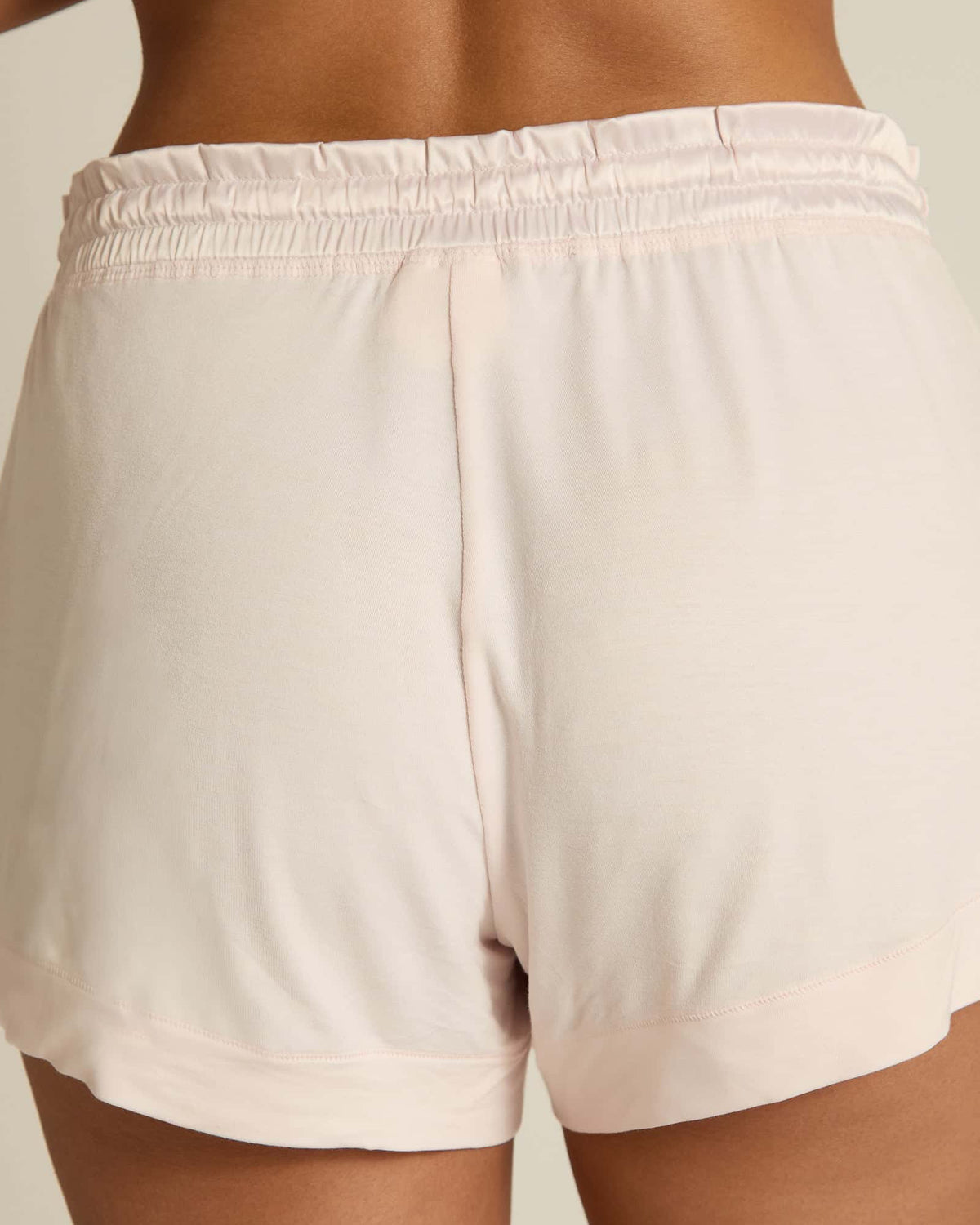 Pink shorts with a drawstring worn by a person on a plain background. The fabric looks light and breathable.