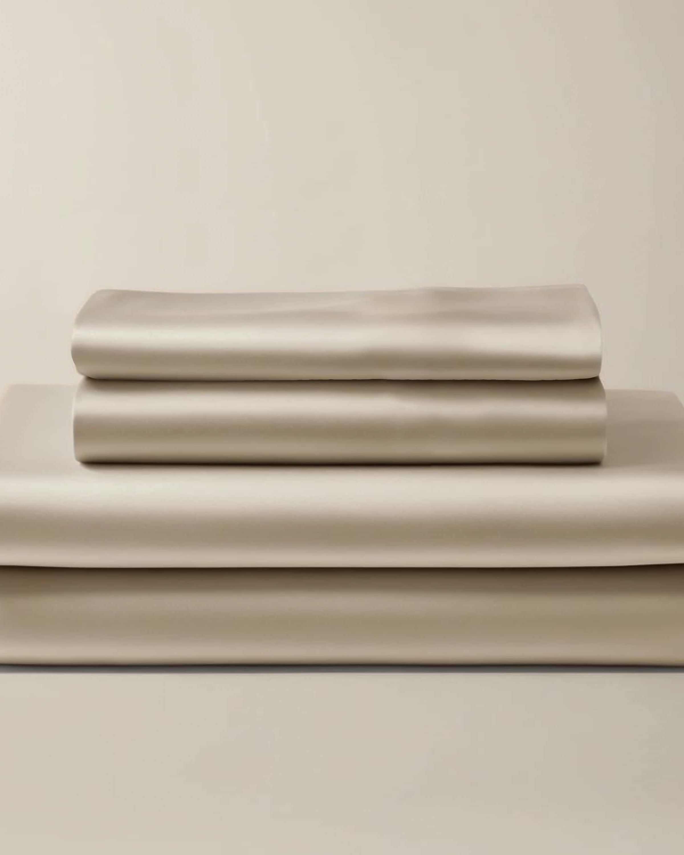 Stack of folded beige bamboo sheets and pillowcases.