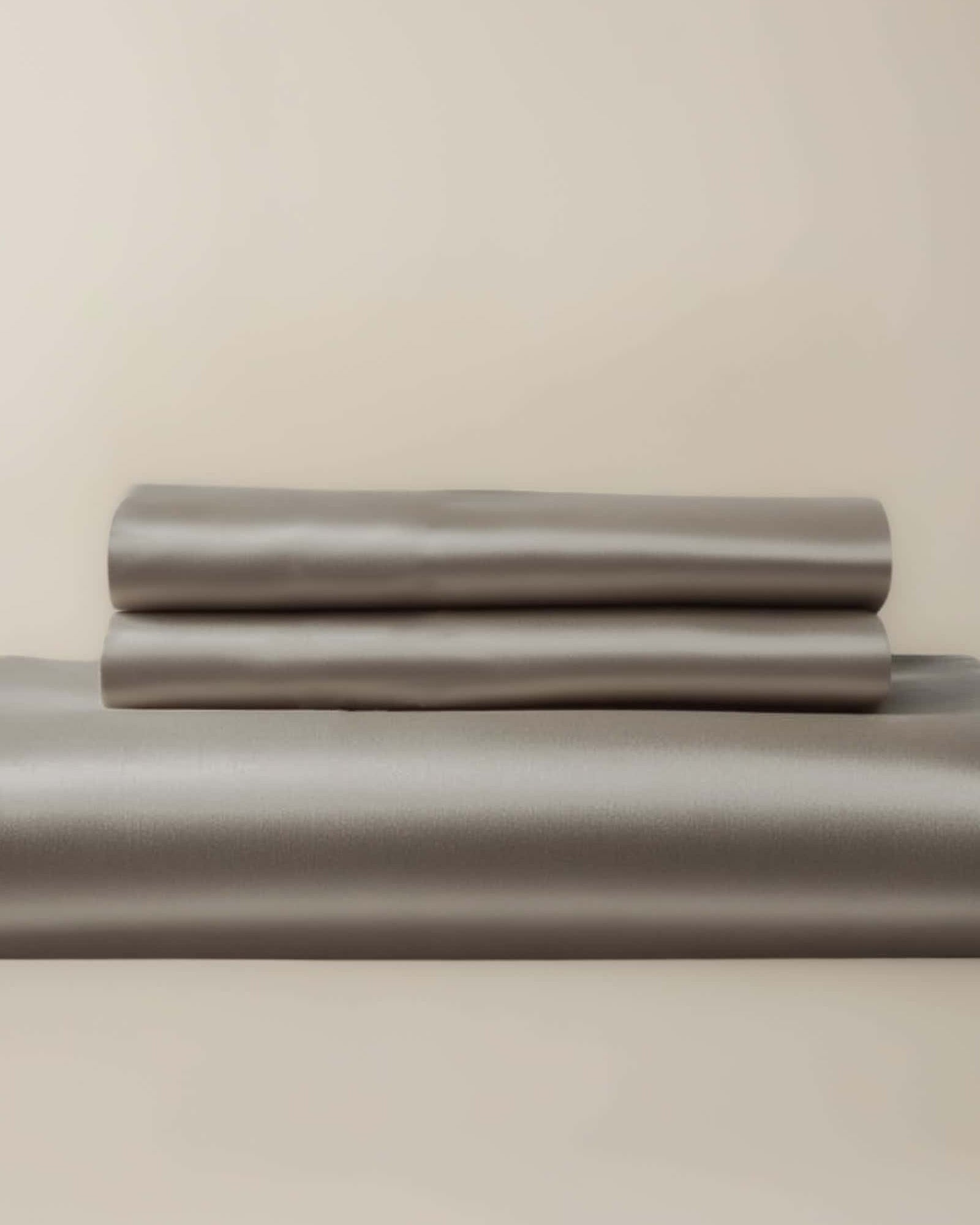 A gray bamboo duvet cover and two pillow shams neatly stacked on a bed.