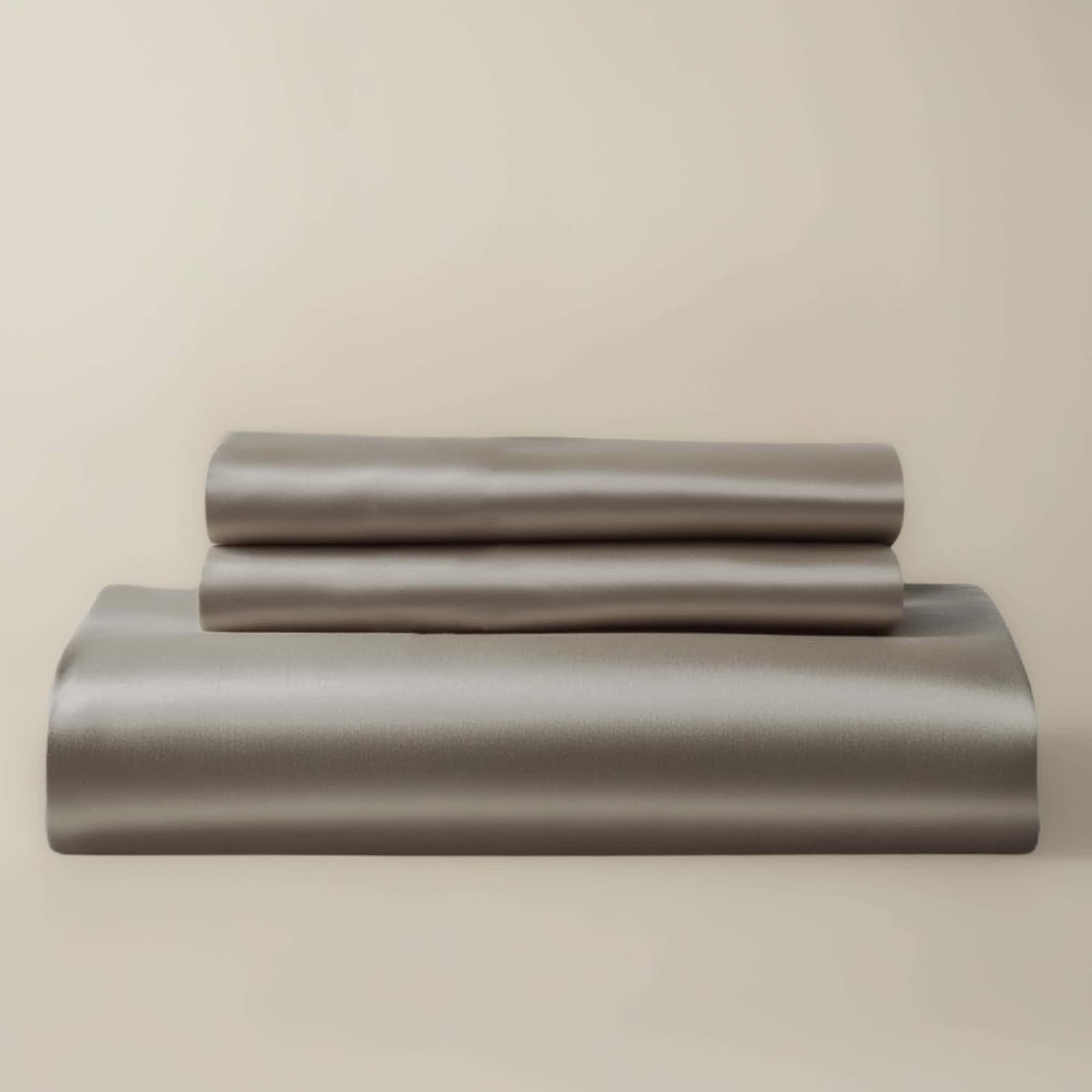 A gray bamboo duvet cover and two pillow shams neatly stacked on a bed.