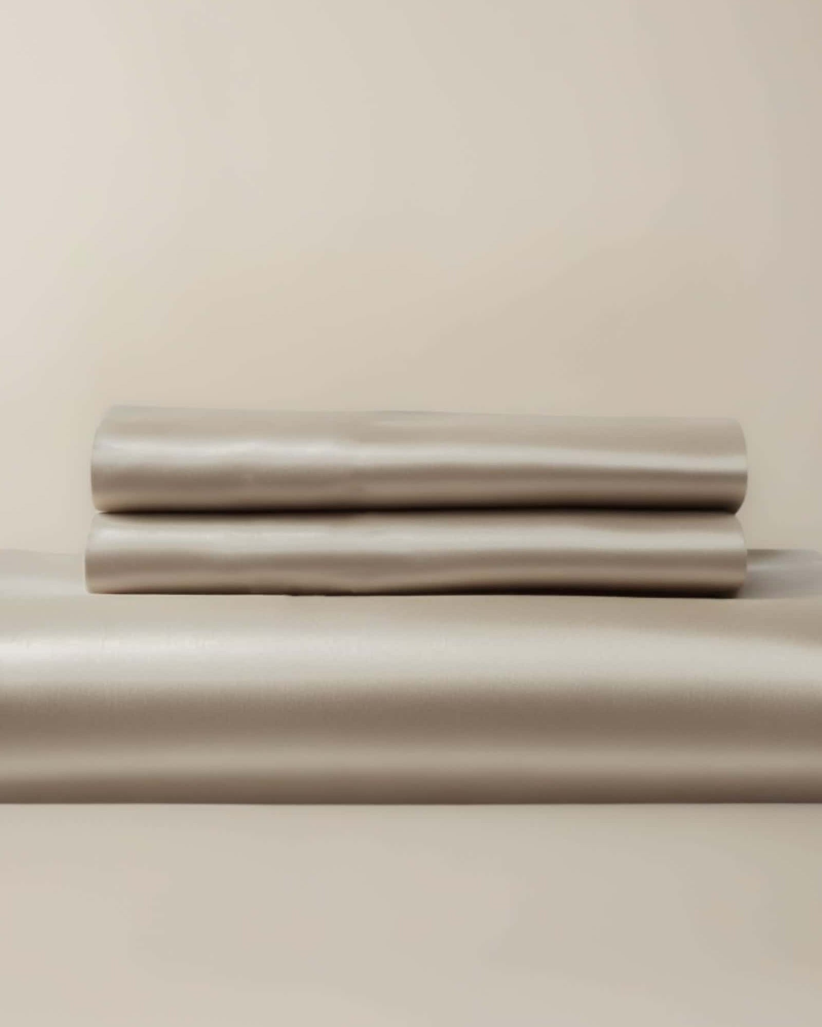 A beige bamboo duvet cover and pillow shams neatly stacked on a bed.