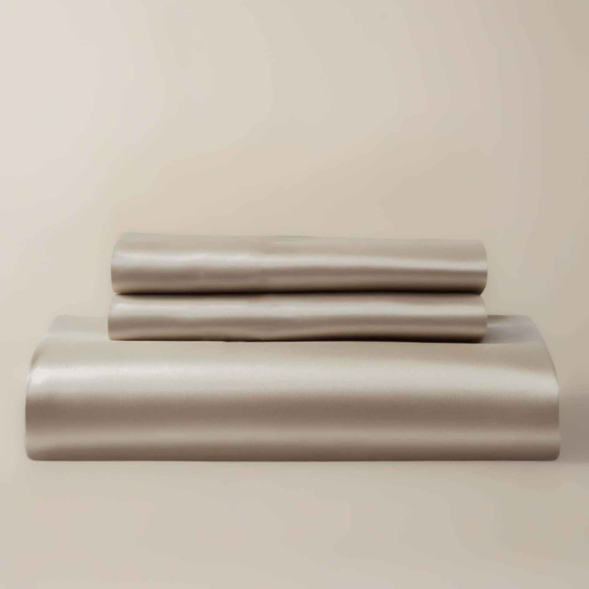 A beige bamboo duvet cover and pillow shams neatly stacked on a bed.