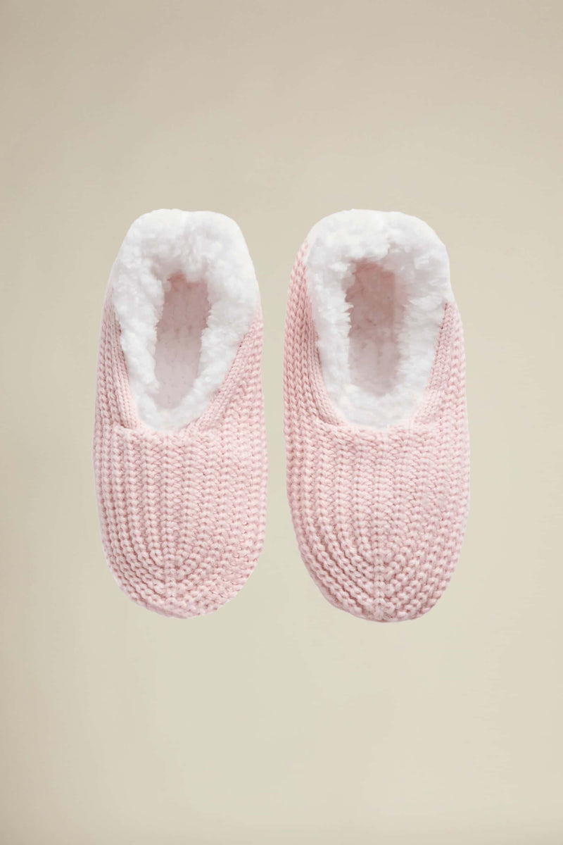 A pair of pink knitted slipper socks with plush lining and skid resistant soles.