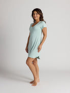 Woman wearing a light blue nightshirt on a plain background