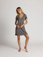 Woman wearing a gray dress against a plain background