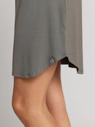 Gray dress partially covering a person's legs on a plain background