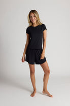 Woman wearing a black shirt and shorts on a plain background