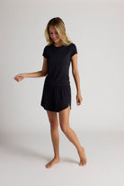 Woman wearing a black shirt and shorts on a plain background