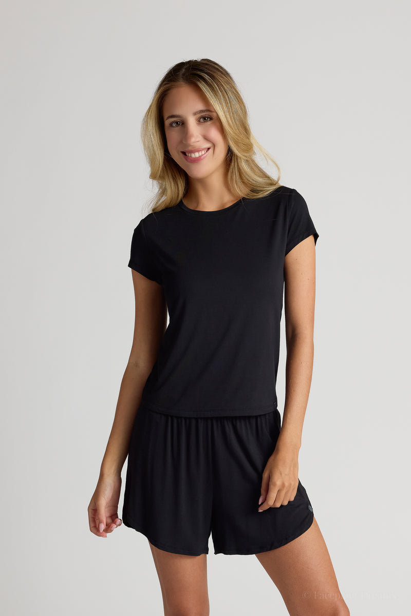 Woman wearing a black shirt and shorts on a plain background