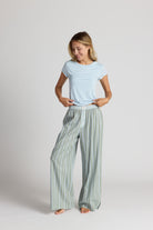 Woman wearing a light blue top and green striped pants on a white background