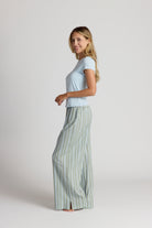 Woman wearing a light blue top and striped pajama pants on a white background