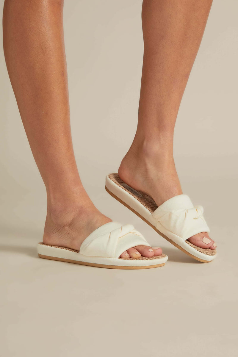 A pair of beige bamboo hemp slides on a person's feet, designed with a natural hemp sole and soft bamboo strap.