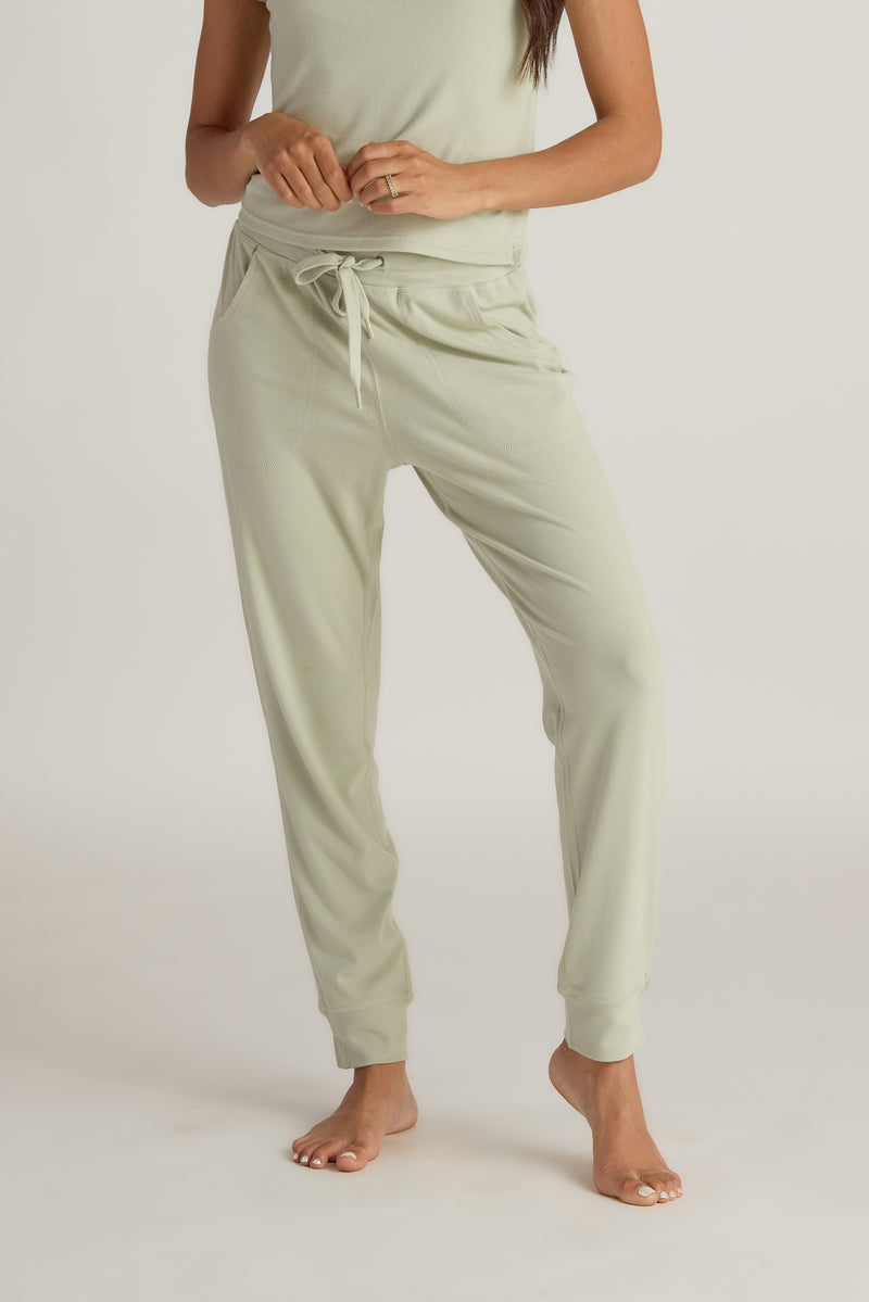 Person wearing light green jogger pants  with a drawstring on a white background