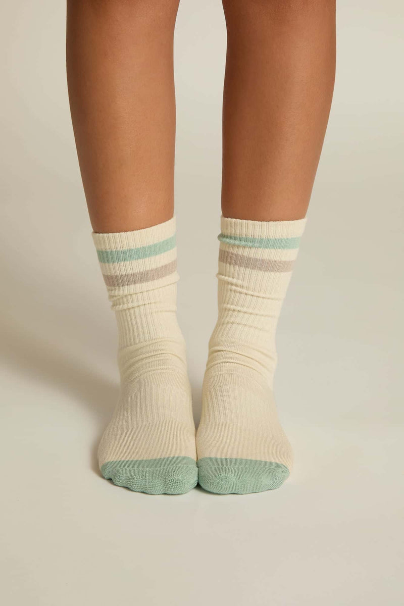 A pair of beige crew socks with light blue stripes and solid blue toes and heels, worn on human feet.