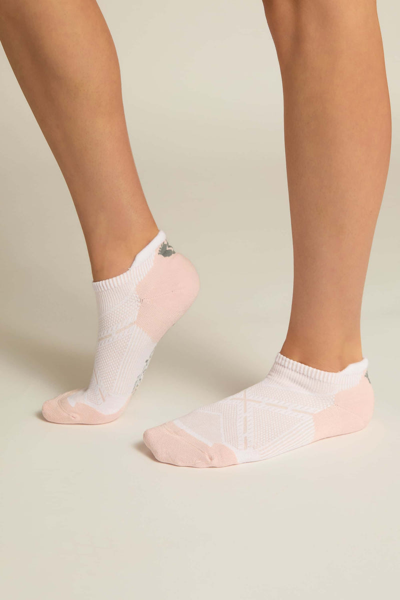 A pair of pink ankle socks with padding at the toe and heel areas, displayed on a person's feet against a white background.