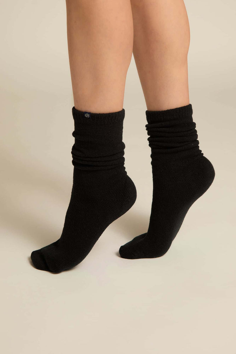 A pair of black luxury lounge socks fit on a person's feet, showcasing the crew height and the soft texture of the bamboo knit blend.