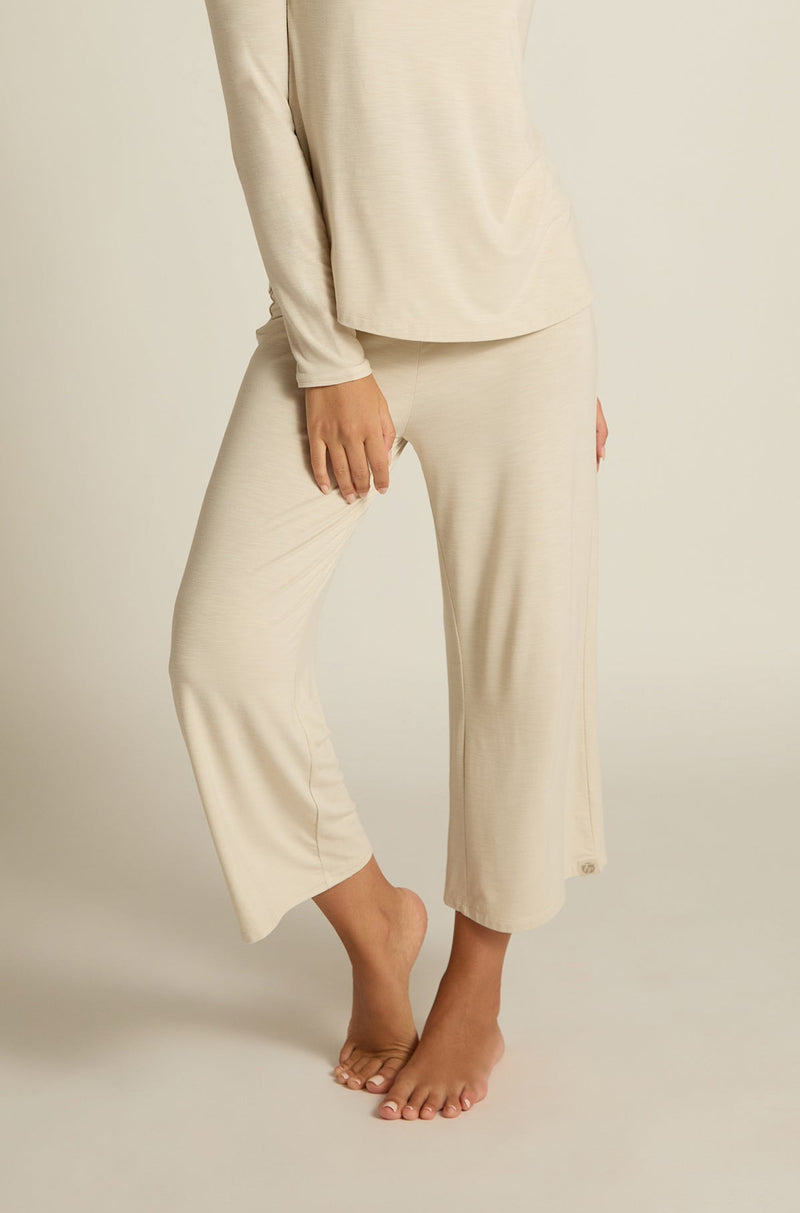A person wearing wide-leg capri pants in a beige color, paired with a matching long-sleeve top.