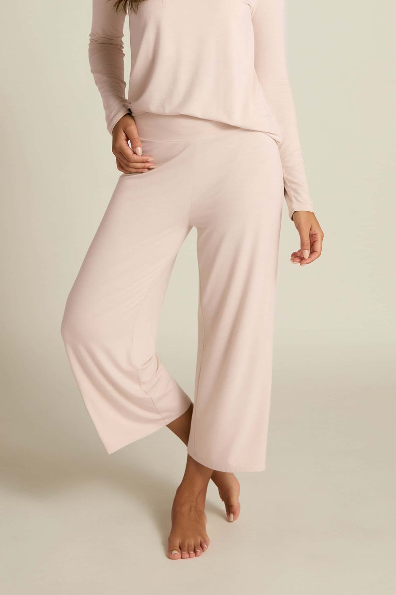 A person wearing wide-leg capri pants in a light pink color, paired with a matching long-sleeve top.