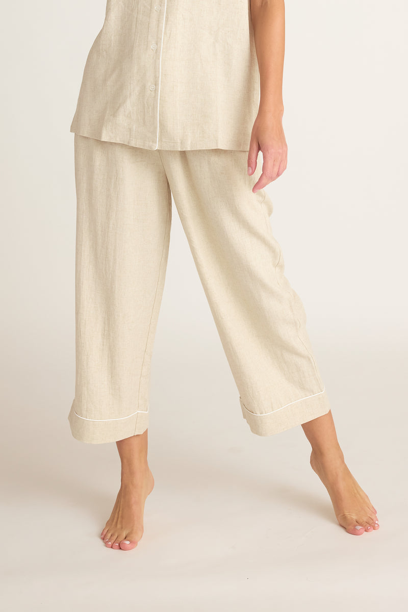 Person wearing beige linen pants and top on a white background
