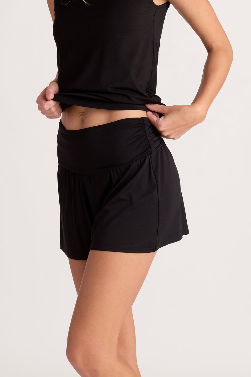 woman wearing black shorts and black sleeveless top on a white background